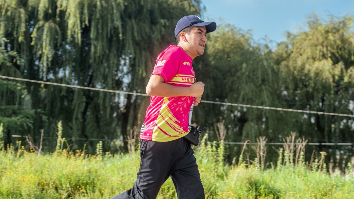 A man in a colorful shirt jogging in a rural area, focusing on endurance and fitness.