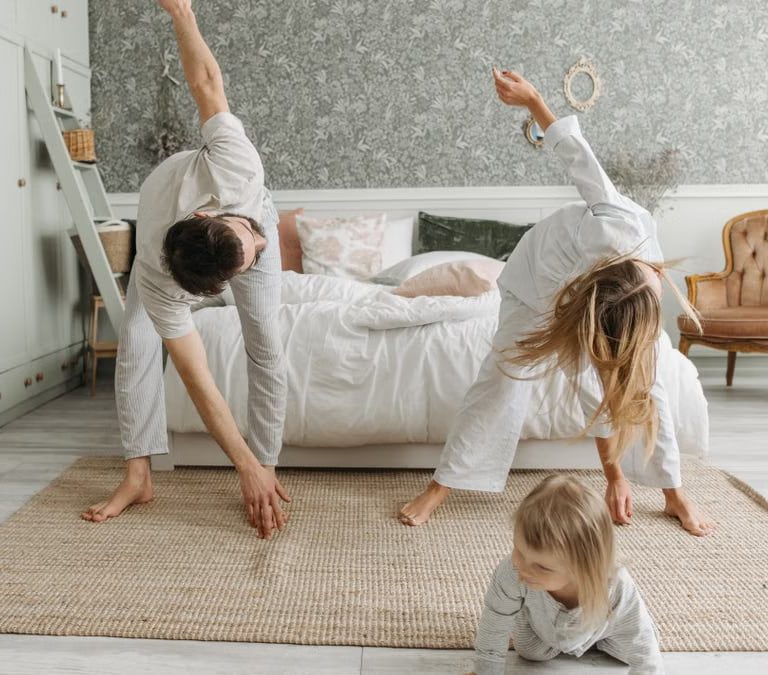 A family stretches together in a cozy bedroom, enjoying morning activities.